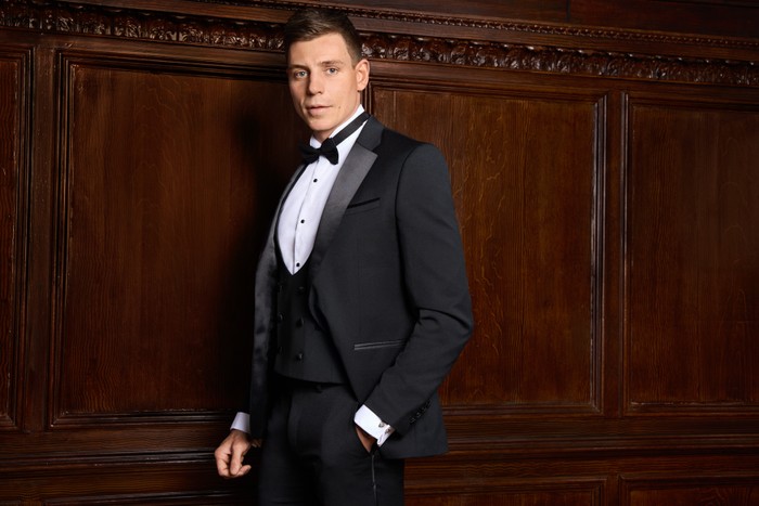 Tristan Phipps pictured for Made in Chelsea. He is wearing a full tuxedo and has his hand in his pocket and is looking ahead.