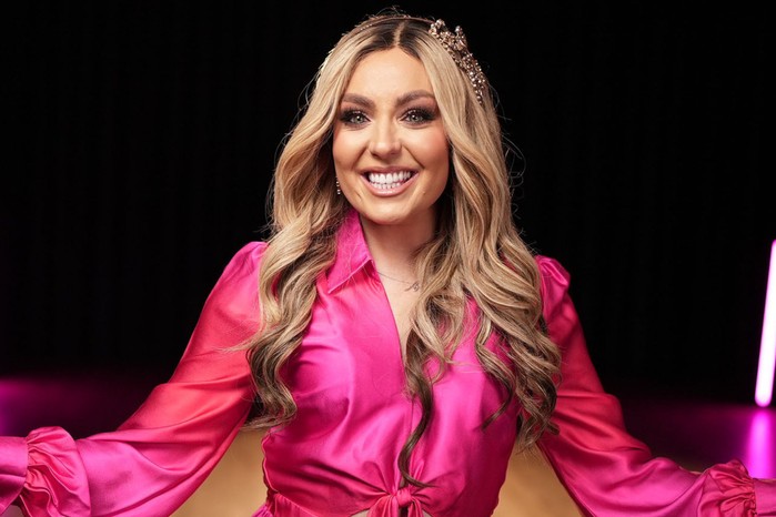 Amy Dowden in a pink dress smiling ahead.