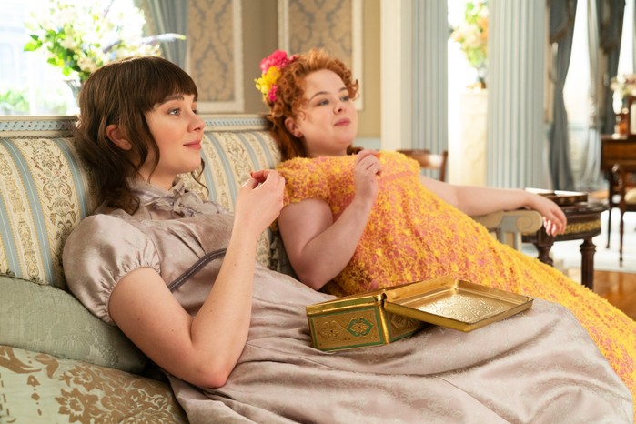 Eloise and Penelope sat next to on another on a couch, eating chocolate