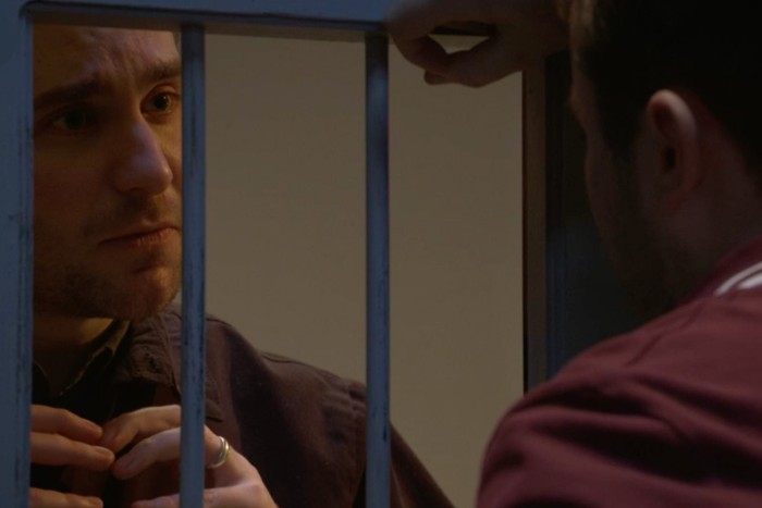 Tony Clay as Callum Highway signing love to Max Bowden as Ben Mitchell through a prison cell window in EastEnders.