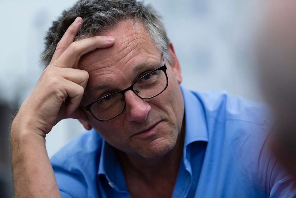 Dr Michael Mosley with his hand to his head talking to someone off screen