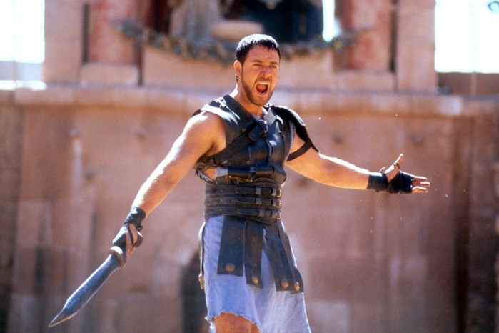 Russell Crowe stars in Gladiator (2000) in gladiatorial gear holding a sword, screaming