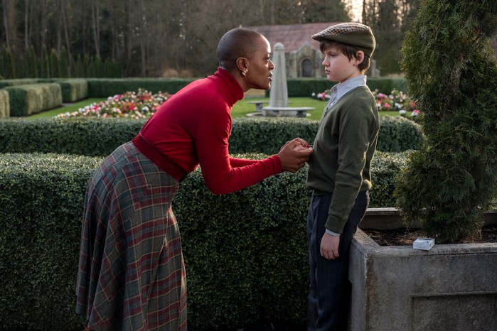 T'Nia Miller as Hannah Grose and Benjamin Evan Ainsworth as Miles in The Haunting of Bly Manor with Grose holding Miles's hand in a country garden