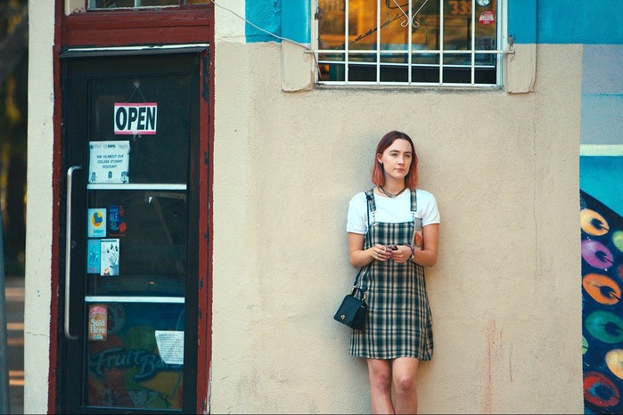 Saoirse Ronan in Lady Bird leaning against a wall in a plaid dress