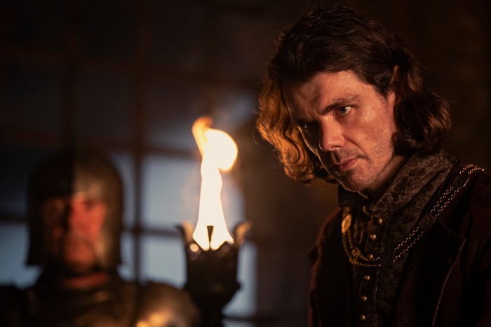 Matthew Needham as Lord Larys Strong against firelight in a castle in House of the Dragon season 2.