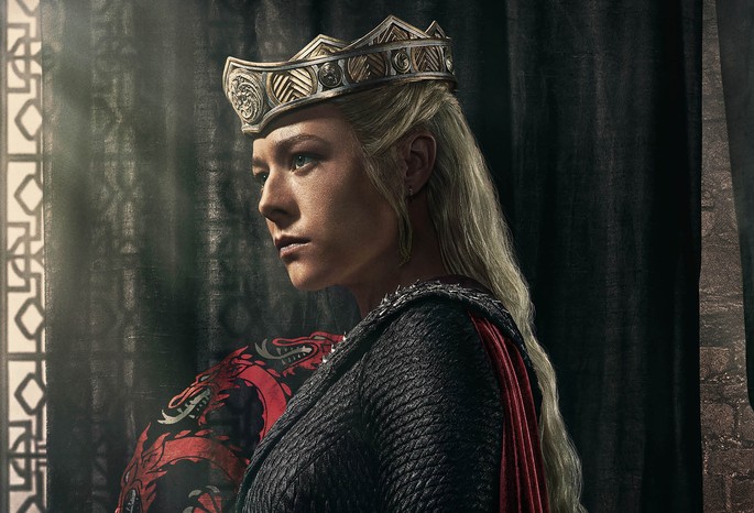 Emma D'Arcy as Queen Rhaenyra Targaryen in a crowd and black roads in front of a black curtain with red dragon Targaryen crest for House of the Dragon season 2.