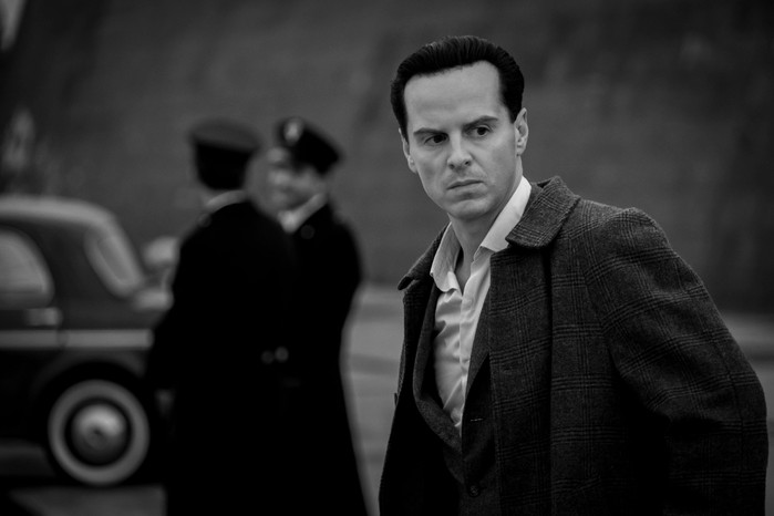 Andrew Scott as Tom Ripley with police in the background in a black-and-white still from Ripley.