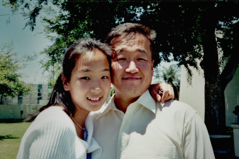 Melanie Lee and Robert Shinn. They are smiling and posing next to one another with Melanie's arm around his neck.