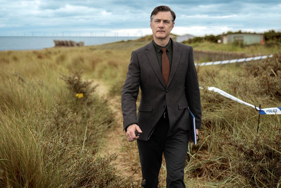 David Morrissey as Ian St Clair in Sherwood, walking along a coastal path in a suit