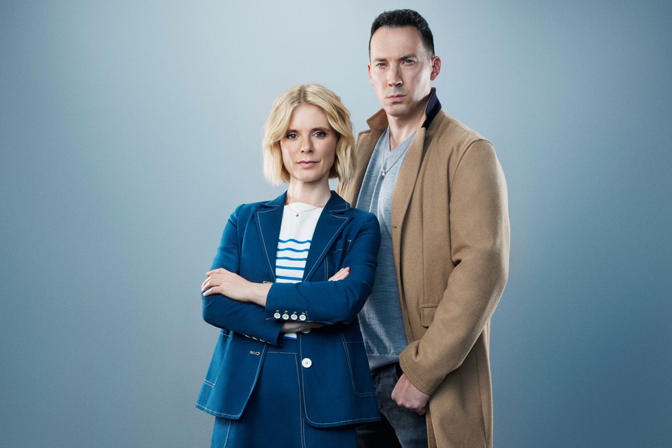 Dr Nikki Alexander (EMILIA FOX), Jack Hodgson (DAVID CAVES) standing next to each other in front of a grey background