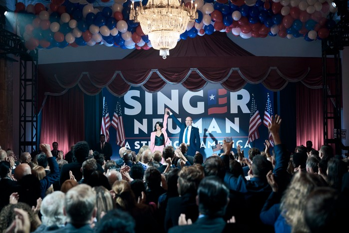 Jim Beaver as Robert Singer and Claudia Doumit as Victoria Neuman in The Boys, stood on a campaign stage together raising their hands in the air together