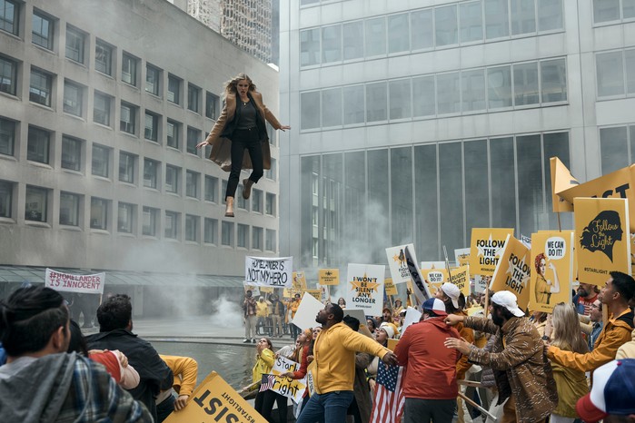 Erin Moriarty as Starlight in The Boys, hovering over a crowd of protestors