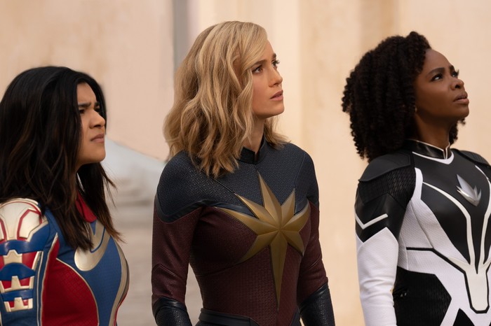 Ms. Marvel (Iman Vellani), Captain Marvel (Brie Larson) and Monica Rambeau (Teyonah Parris) in The Marvels looking skywards, confused