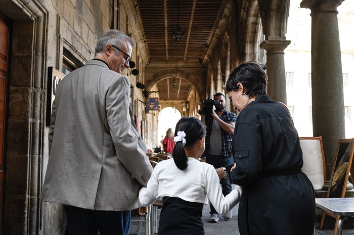 Tristán Ulloa as Alfonso, Iris Wu as Asunta, Candela Peña as Rosario walking hand in hand through a busy street in The Asunta Case.