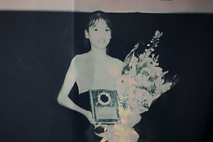 A photo go a young Jennifer Pan holding flowers and a framed certificate.